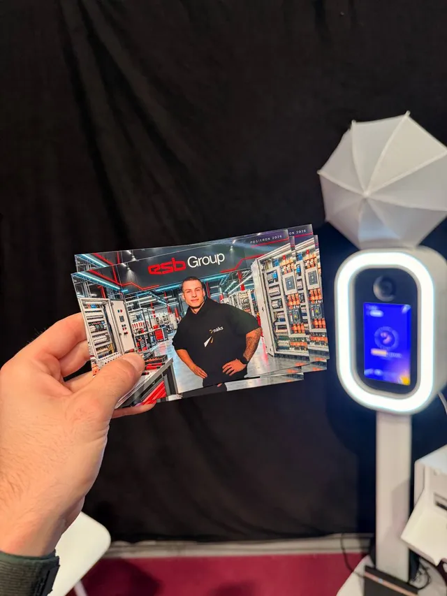 Prinditud fotod ESB Group taustaga ja „Positron 2026“ kujundusega, taga Naks fotoboks